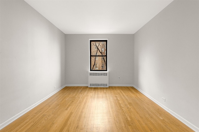 empty room featuring radiator heating unit and light hardwood / wood-style floors