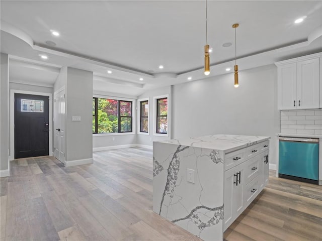 kitchen featuring tasteful backsplash, white cabinetry, dishwasher, and a center island