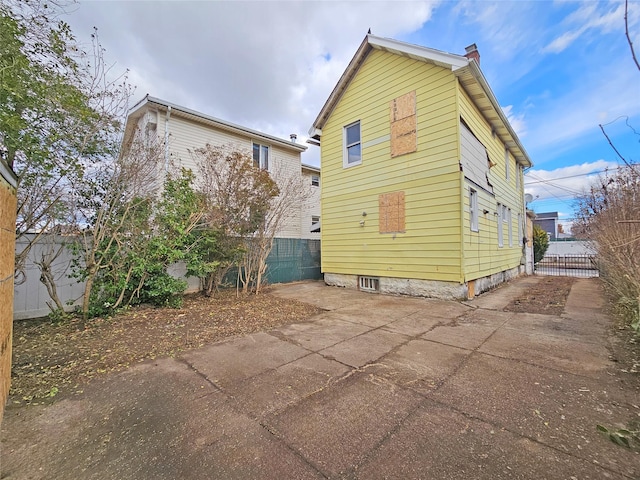 129-06 131st St, South Ozone Park, NY 11420 - rear view of property featuring a chimney, a patio area, and concrete driveway