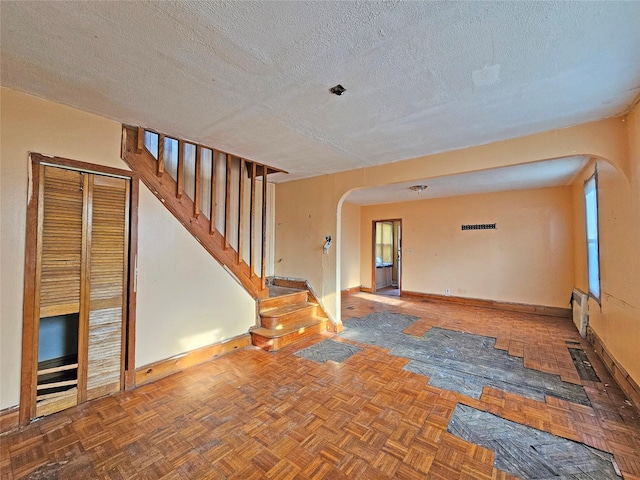 129-06 131st St, South Ozone Park, NY 11420 - unfurnished room featuring arched walkways, a textured ceiling, and stairs