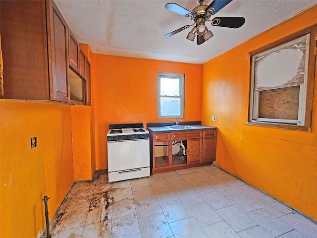 129-06 131st St, South Ozone Park, NY 11420 - kitchen with gas range gas stove, brown cabinetry, a ceiling fan, and dark countertops