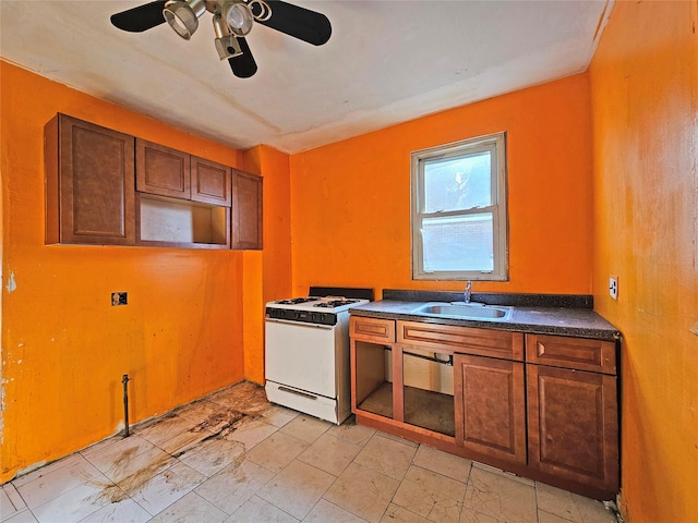 129-06 131st St, South Ozone Park, NY 11420 - kitchen featuring white gas stove, ceiling fan, dark countertops, and brown cabinetry