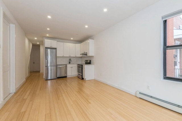 kitchen featuring a baseboard heating unit, backsplash, appliances with stainless steel finishes, white cabinets, and light wood-type flooring