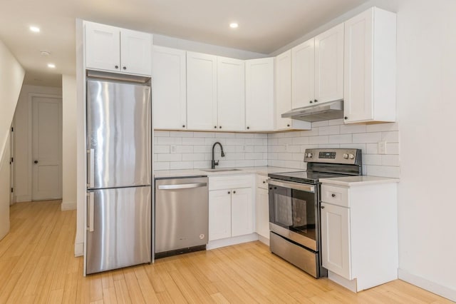 kitchen with white cabinetry, sink, stainless steel appliances, light hardwood / wood-style floors, and decorative backsplash