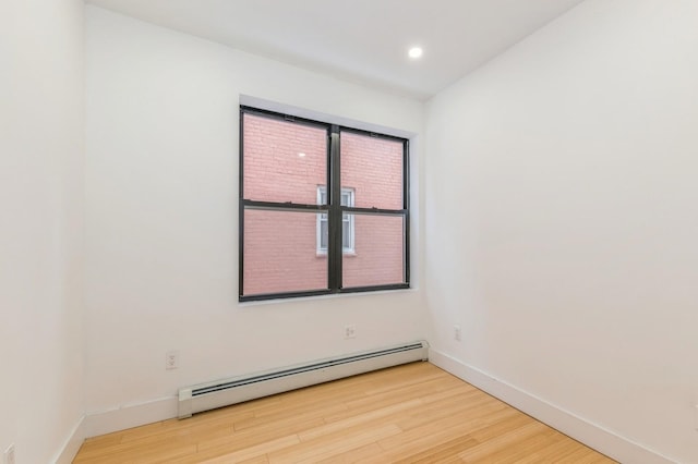 empty room featuring a baseboard radiator and hardwood / wood-style flooring