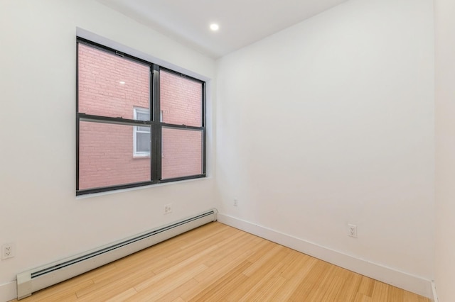 empty room with baseboard heating and wood-type flooring