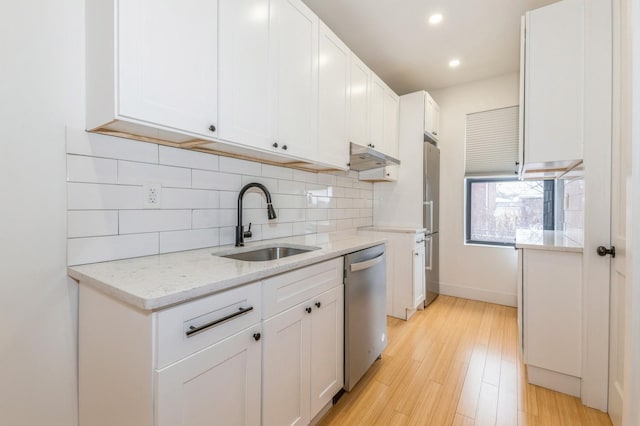 kitchen featuring light stone countertops, sink, stainless steel appliances, light hardwood / wood-style flooring, and white cabinets