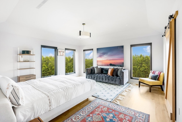 bedroom featuring a barn door and light wood-type flooring