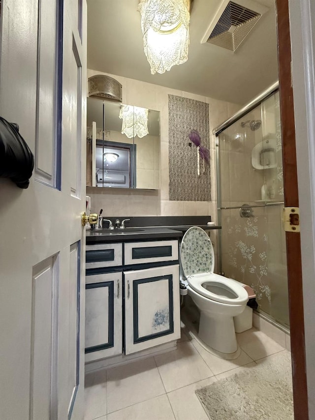 bathroom featuring a shower with door, tile patterned flooring, vanity, and toilet