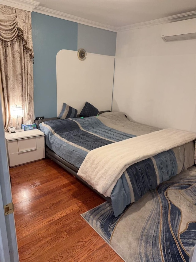 bedroom featuring dark wood-type flooring, crown molding, and a wall unit AC