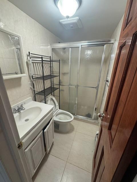 bathroom with toilet, vanity, tile patterned flooring, and walk in shower