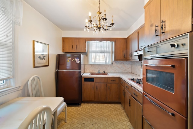 kitchen with decorative backsplash, stainless steel appliances, sink, a chandelier, and hanging light fixtures