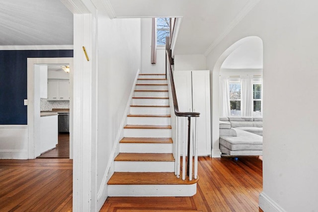 stairs featuring wood-type flooring and crown molding