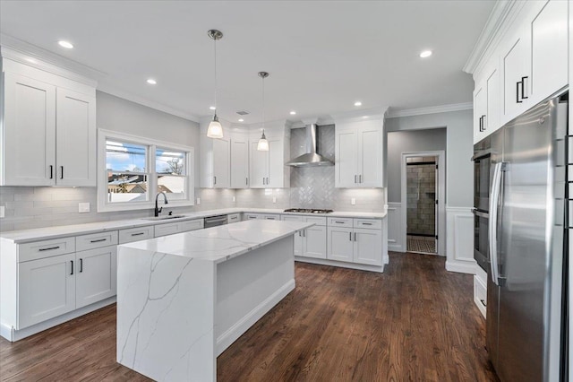 kitchen featuring white cabinetry, hanging light fixtures, wall chimney range hood, a kitchen island, and appliances with stainless steel finishes