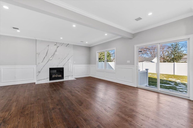 unfurnished living room with beam ceiling, a premium fireplace, hardwood / wood-style floors, and ornamental molding