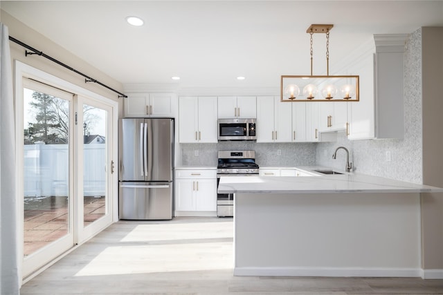 kitchen with pendant lighting, white cabinetry, sink, and appliances with stainless steel finishes