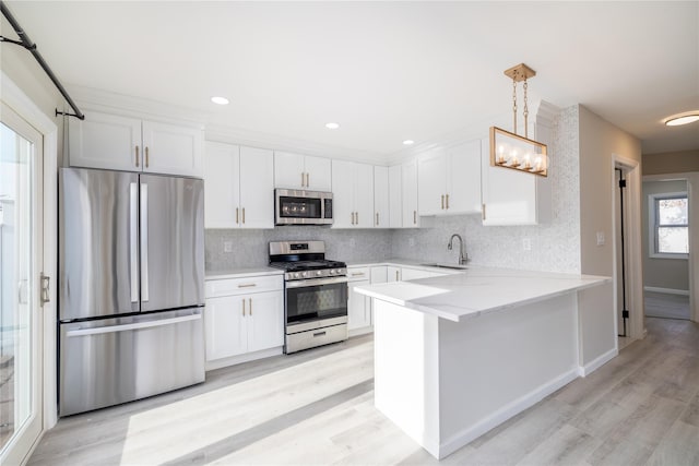 kitchen featuring appliances with stainless steel finishes, white cabinetry, hanging light fixtures, and sink