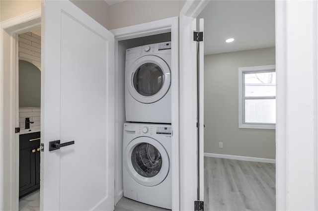 laundry area with light hardwood / wood-style floors and stacked washer and clothes dryer