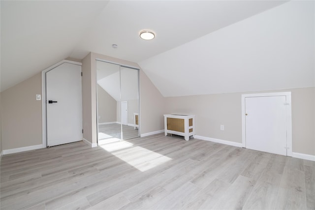 bonus room with light wood-type flooring and vaulted ceiling