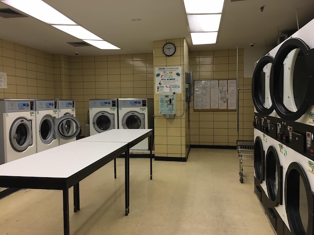 clothes washing area with tile walls, washer and clothes dryer, and stacked washer and clothes dryer