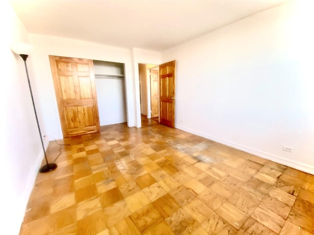 unfurnished bedroom featuring a closet and light parquet flooring