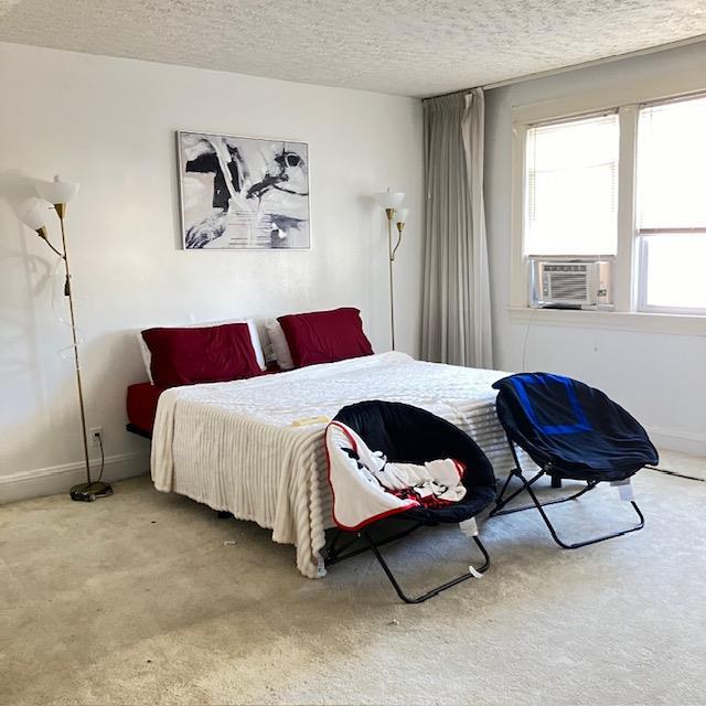 bedroom featuring carpet floors, cooling unit, and a textured ceiling