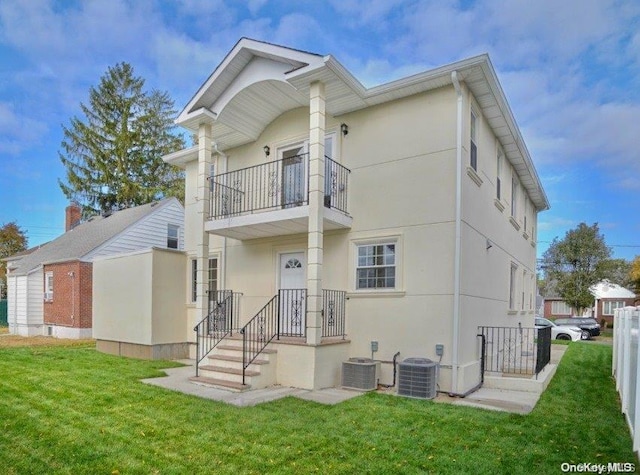 rear view of house with central AC and a yard