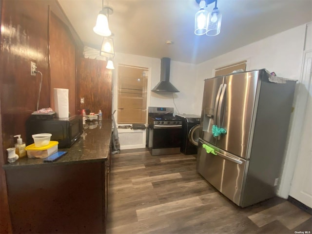 kitchen with pendant lighting, wall chimney range hood, dark hardwood / wood-style floors, washer / dryer, and stainless steel appliances