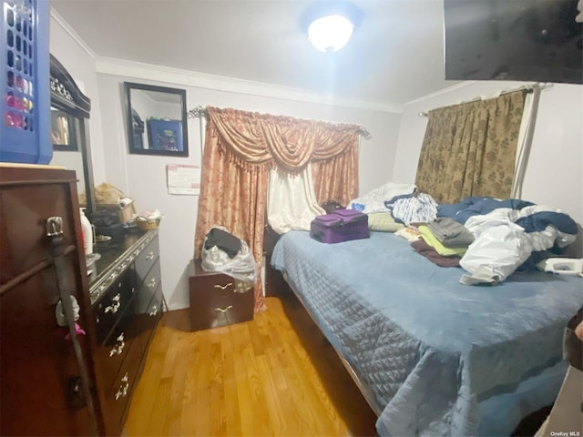 bedroom featuring crown molding and light hardwood / wood-style flooring