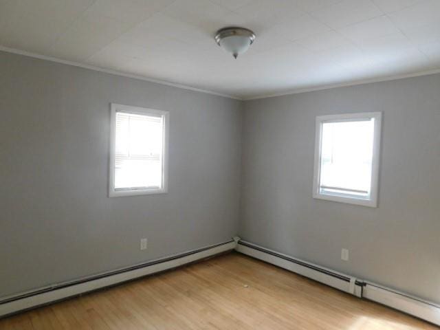 unfurnished room with crown molding, baseboard heating, and light hardwood / wood-style flooring