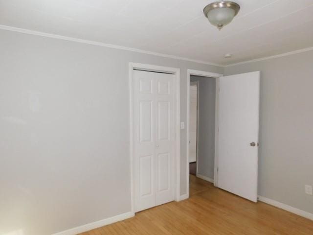 unfurnished bedroom featuring a closet, hardwood / wood-style floors, and ornamental molding