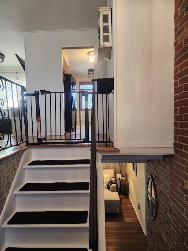 stairs featuring hardwood / wood-style floors and ornamental molding