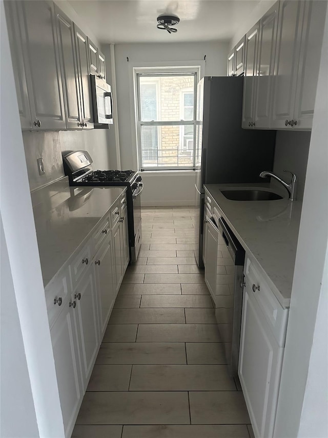 kitchen featuring light stone countertops, sink, white cabinetry, and stainless steel appliances