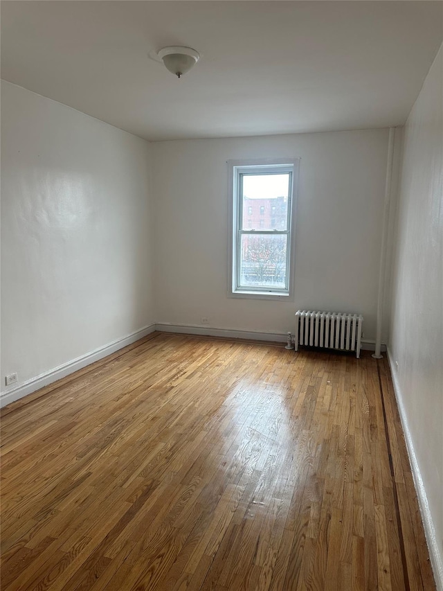 spare room with light wood-type flooring and radiator