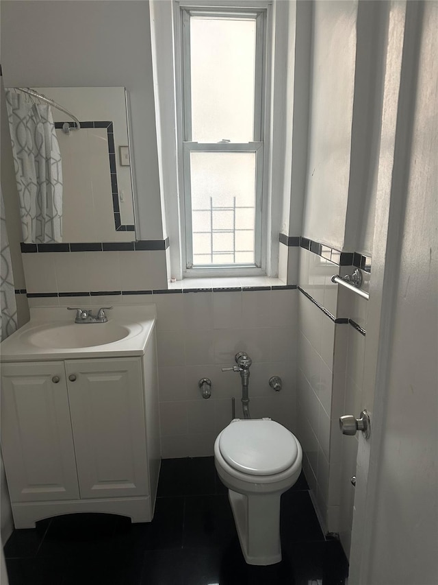 bathroom with vanity, toilet, and tile walls