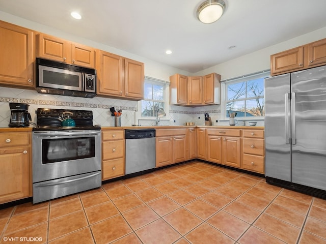 kitchen featuring appliances with stainless steel finishes, backsplash, light tile patterned floors, and a wealth of natural light