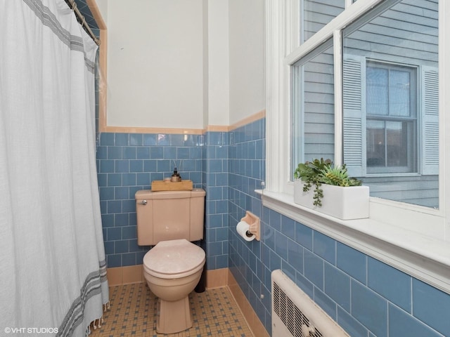 bathroom featuring tile patterned flooring, toilet, and tile walls