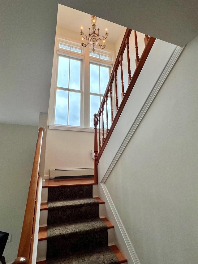 stairs with an inviting chandelier and baseboard heating