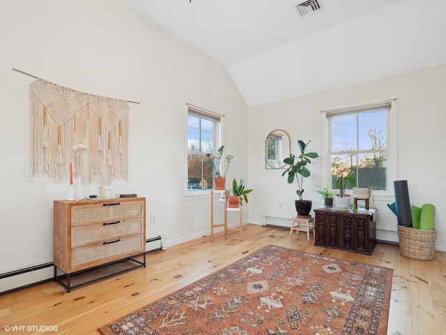 living area featuring hardwood / wood-style flooring, vaulted ceiling, and baseboard heating