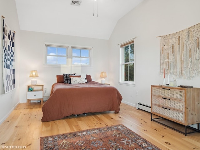 bedroom with wood-type flooring, a baseboard heating unit, and lofted ceiling