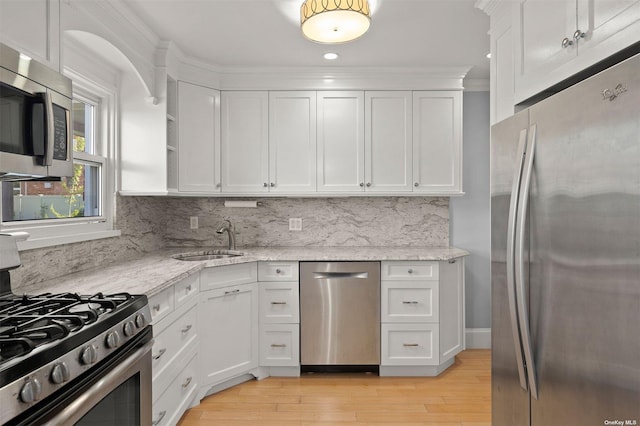 kitchen with white cabinets, sink, decorative backsplash, light stone countertops, and stainless steel appliances