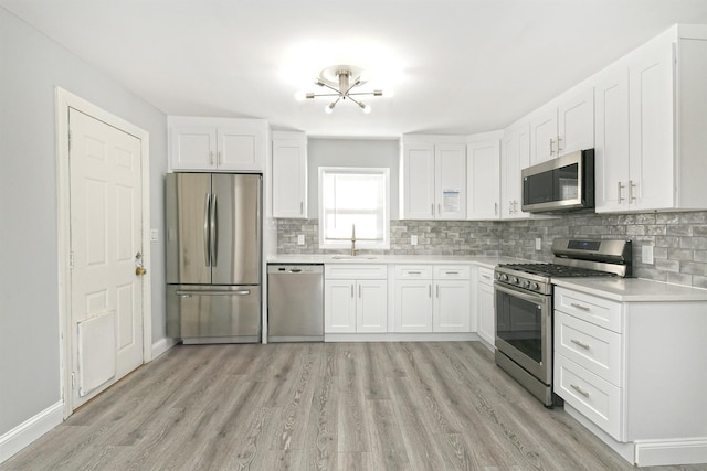 kitchen with white cabinets, sink, decorative backsplash, light hardwood / wood-style floors, and stainless steel appliances