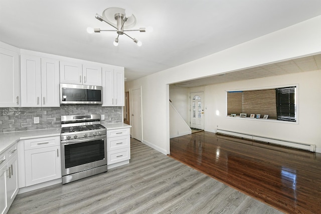 kitchen featuring white cabinets, decorative backsplash, stainless steel appliances, and a baseboard heating unit