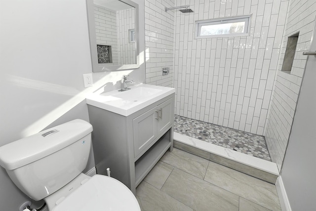 bathroom featuring a tile shower, vanity, toilet, and tile patterned floors