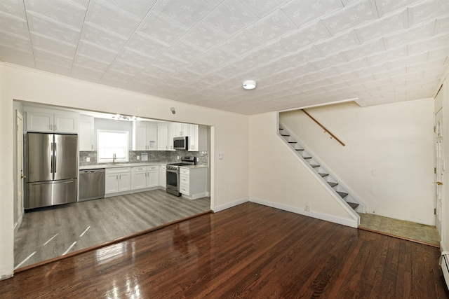 kitchen featuring sink, stainless steel appliances, decorative backsplash, white cabinets, and hardwood / wood-style flooring