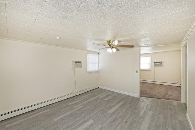 spare room featuring a wall mounted air conditioner, wood-type flooring, ceiling fan, and a baseboard heating unit