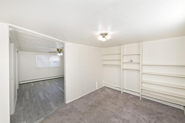 carpeted spare room with a baseboard heating unit