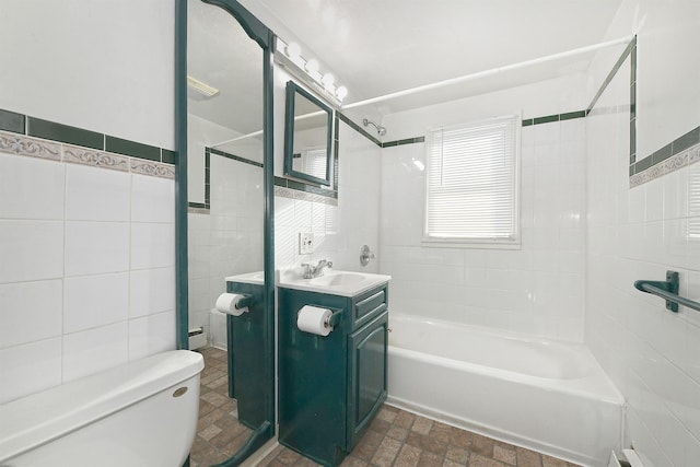 full bathroom featuring tiled shower / bath, vanity, toilet, and tile walls