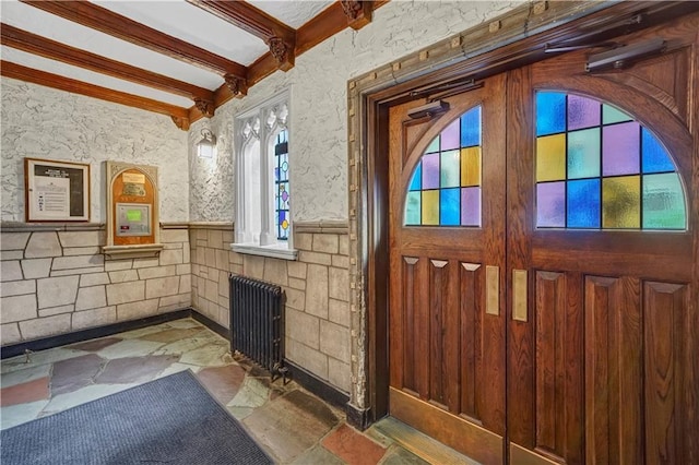 interior space with radiator heating unit and vaulted ceiling with beams