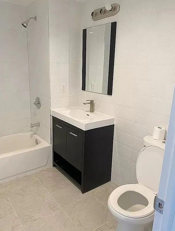 full bathroom with vanity, tiled shower / bath combo, and toilet